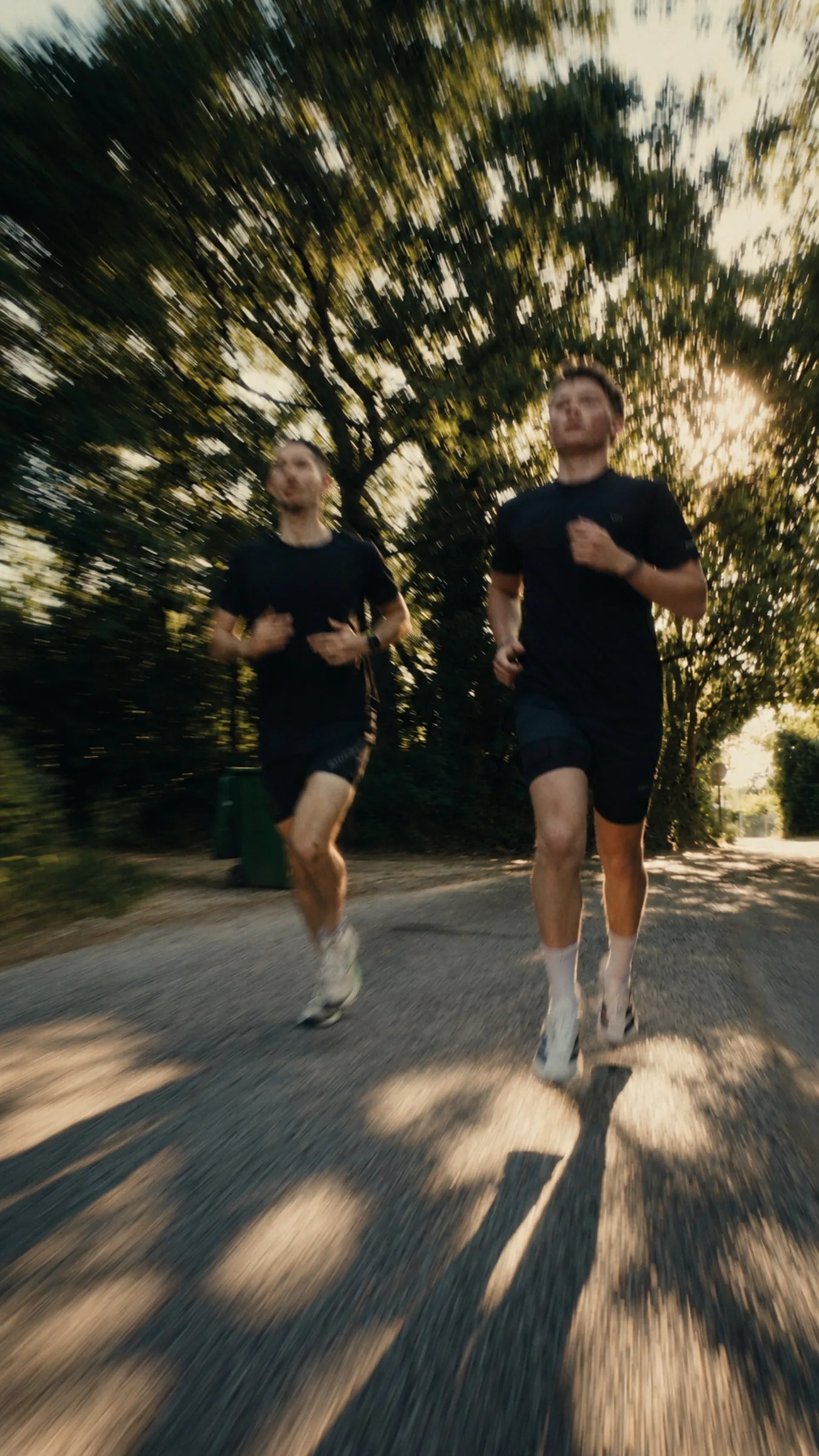 Deux coureurs de NULLL.CLUB courent côte à côte sur un chemin bordé d’arbres